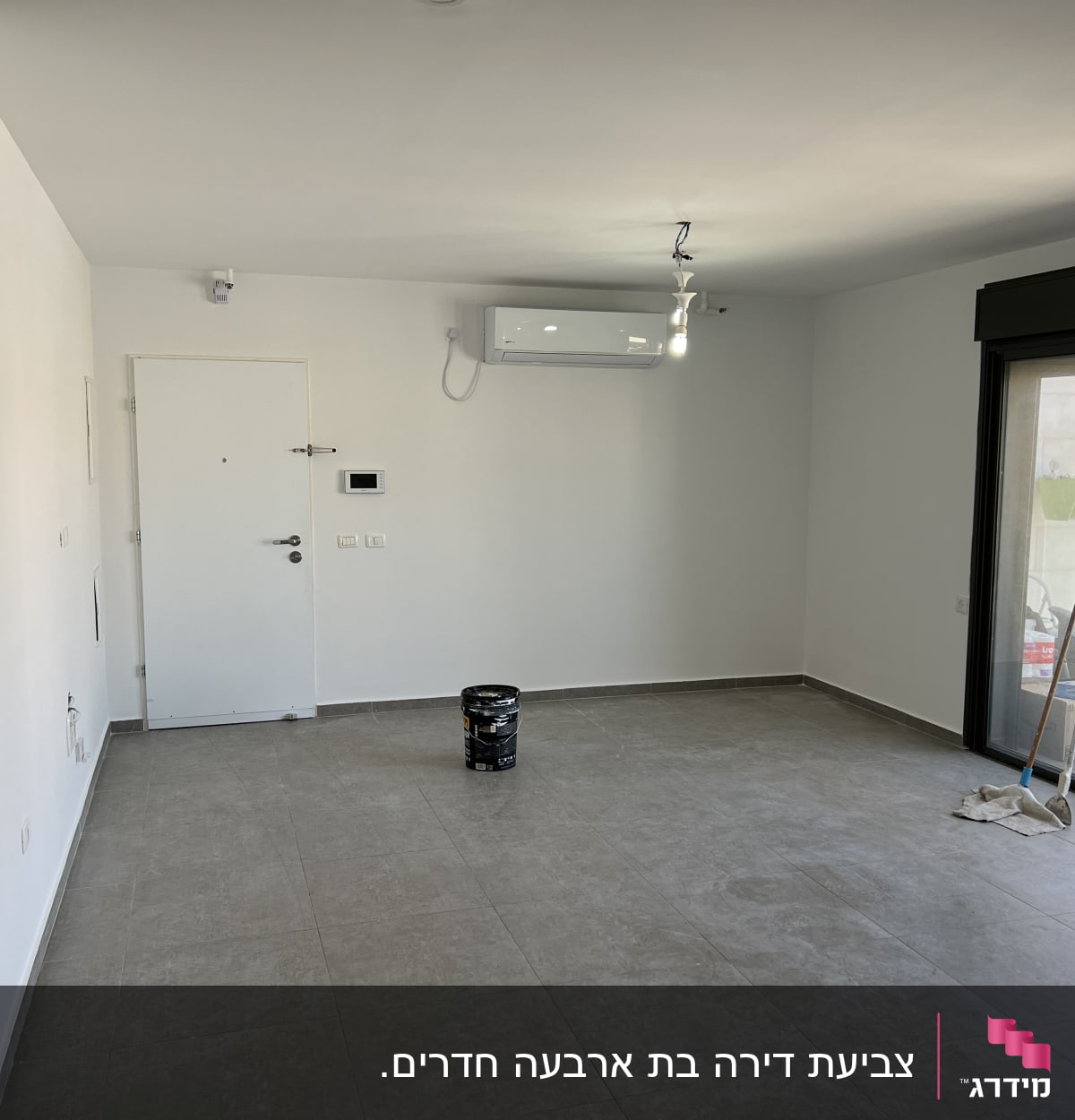 דלי צבע שחור ומברשות על רצפה בחדר ריק